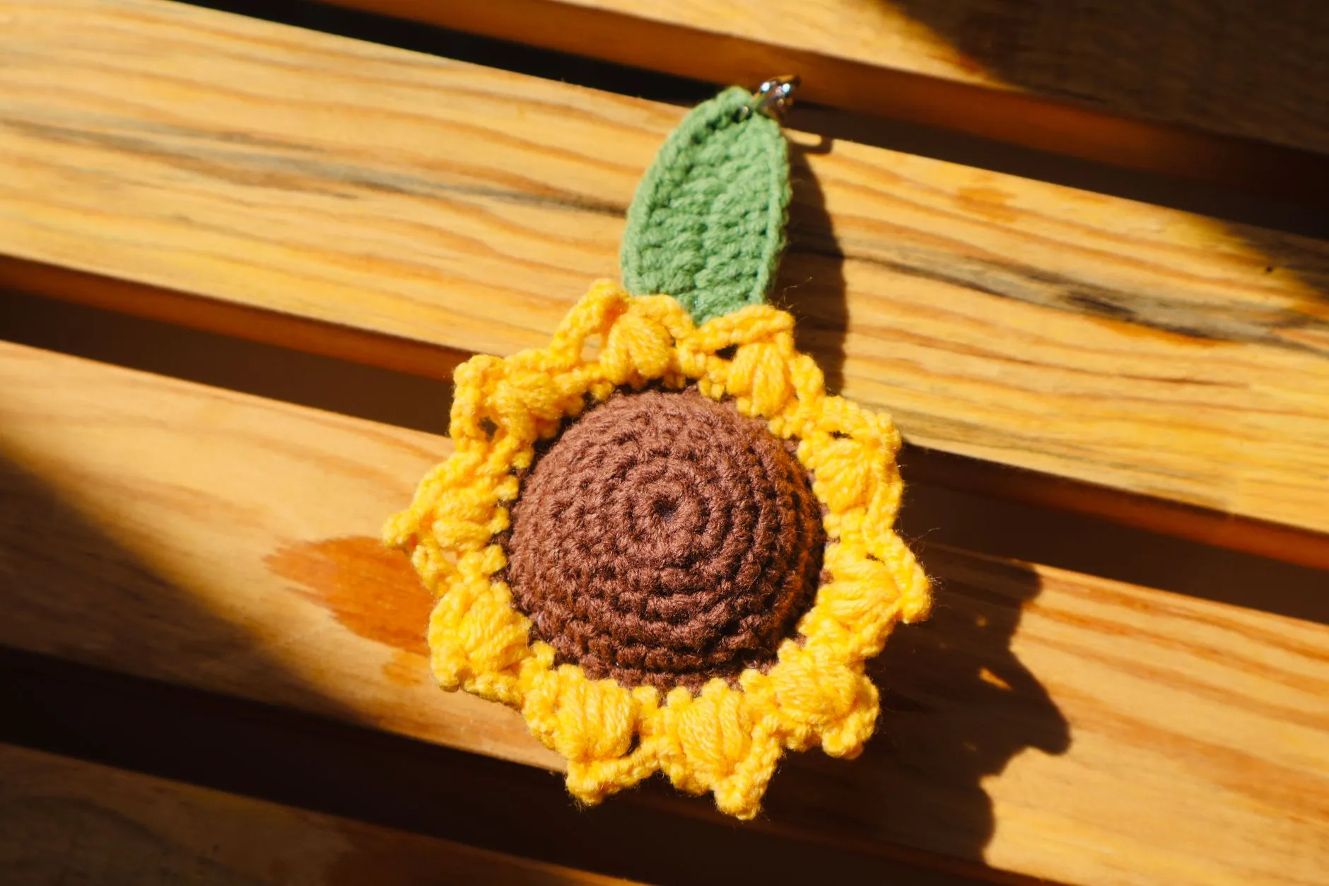 Un porte clé au crochet en forme d'amigurumi, posé à côté du fil et du crochet utilisés pour le réaliser